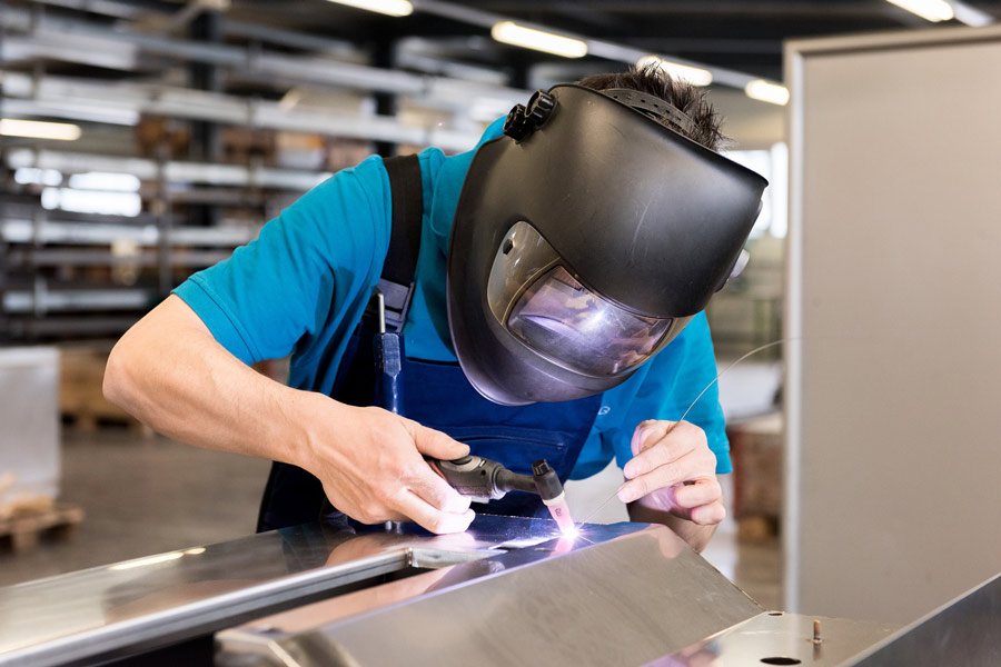 A man welding wearing a welding helmet, denoting the best welding tools you need for your welding work.