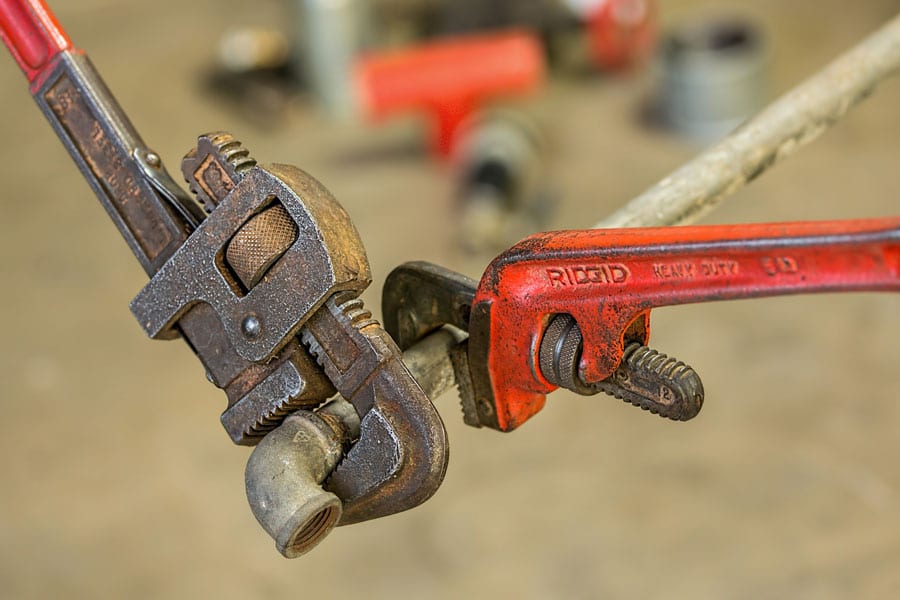 Image of a pipe wrench denoting the tools of a pipelayer