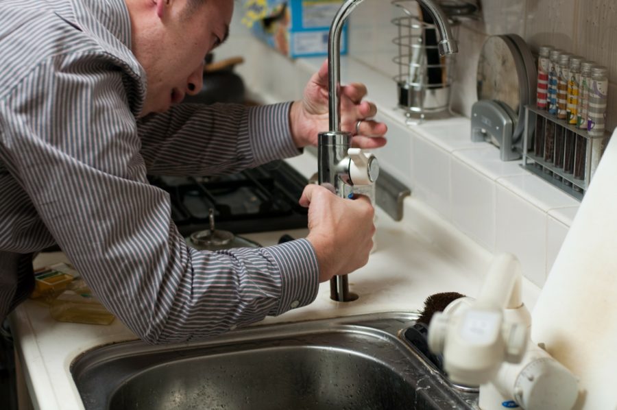 A man repairing a tap indicating how to be a building maintenance worker