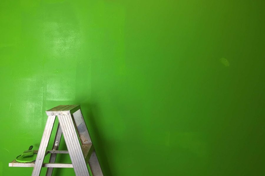 A ladder which is kept next to a green wall