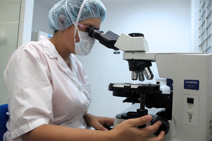 A woman inspecting an objective using a microscope that gives us an idea of the history of microscopes