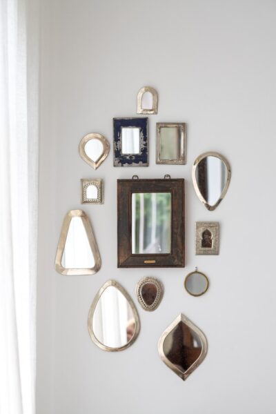 Image of different shapes and sizes of mirrors hanging as wall decor